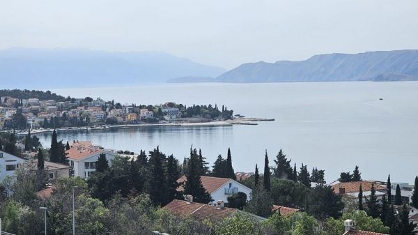 View of a coastal town in Croatia with several buildings and a clear view of the sea in the background. Real estate Croatia, apartment with sea view