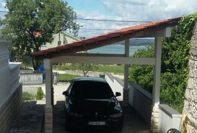 Carport and in the background the garden and a view of the sea.