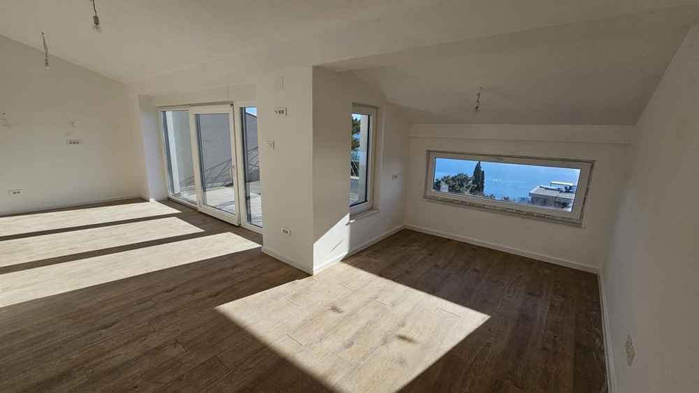Empty interior of an apartment for sale in Crikvenica, with large windows with scenic sea views and wooden floors