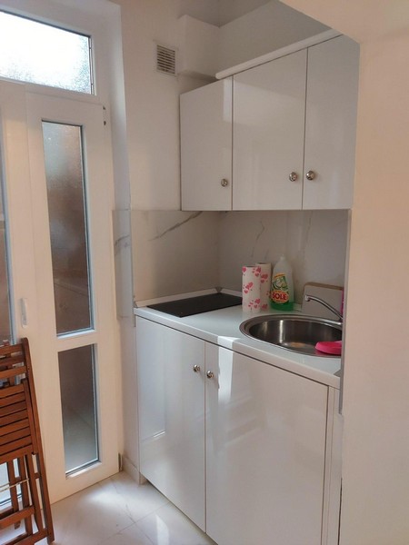 Small, white kitchen and access to the storage area.