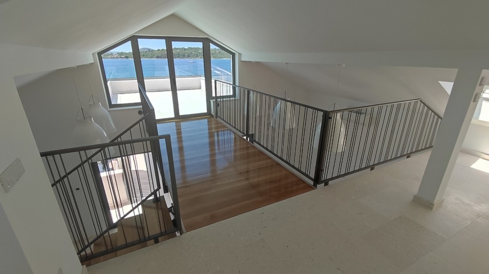 Real Estate Croatia - Spacious penthouse gallery with wooden floors and glass railings offering open sea views and bright rooms, presented by Panorama Scouting.