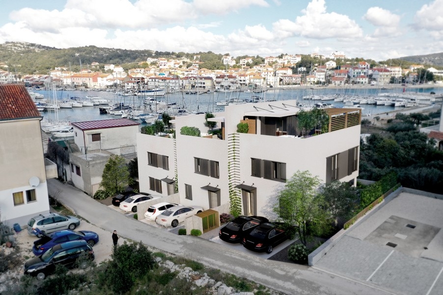 Aerial view of a property in Croatia with parking spaces and a view of the picturesque harbor.