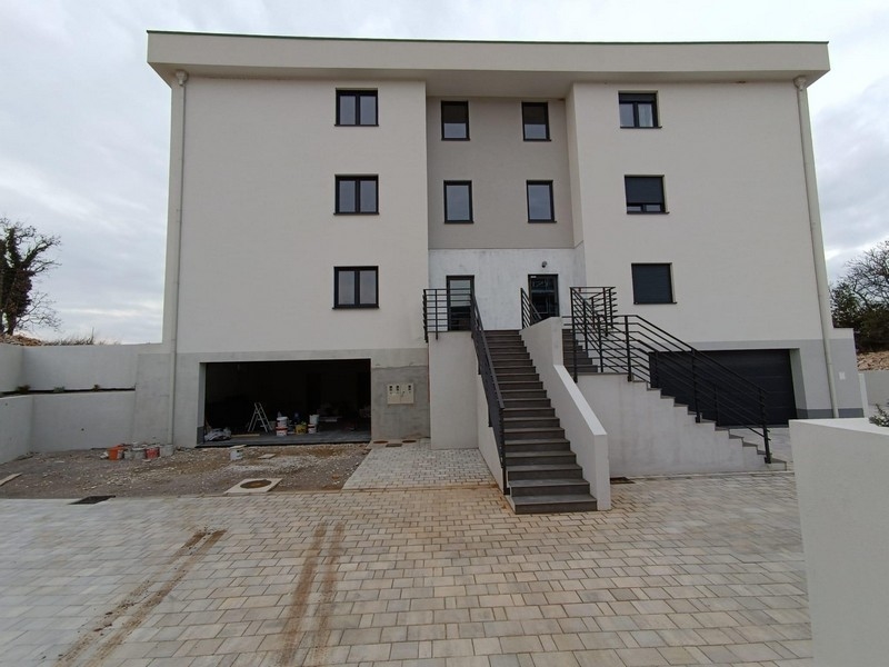 Front view of a new white apartment building in Croatia with a paved driveway and external stairs