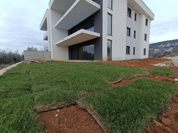 Freshly laid turf on the lawn of a contemporary Croatian apartment with a white modern building in the background