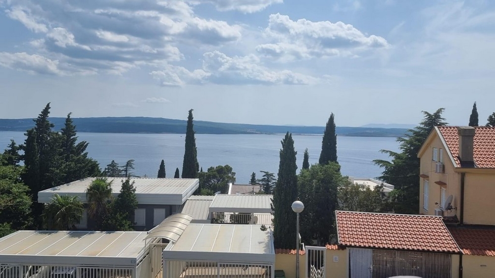 Elevated view of residential rooftops in Crikvenica with the Adriatic Sea in the background, highlighting the proximity to the coast, listed by Panorama Scouting.