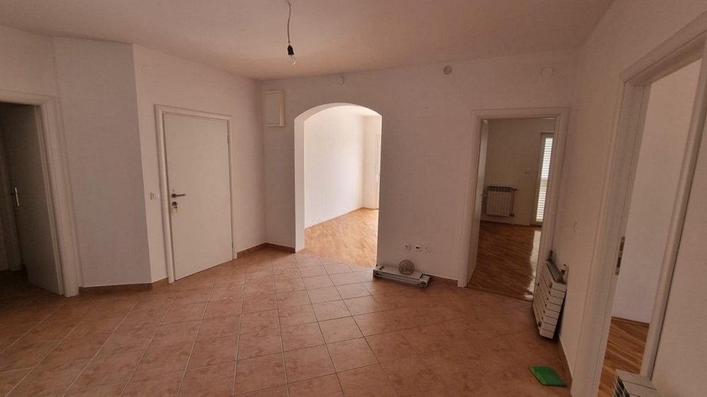Interior view of a light-filled, empty apartment with tiled floors, showing the open arched walkway to adjacent rooms, for sale in Crikvenica by Panorama Scouting.