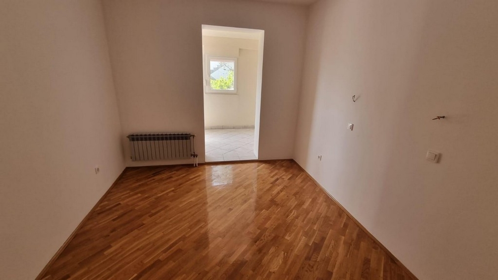 Empty bedroom with polished wooden floor and a window, in an on-market apartment in Crikvenica, presented by Panorama Scouting.