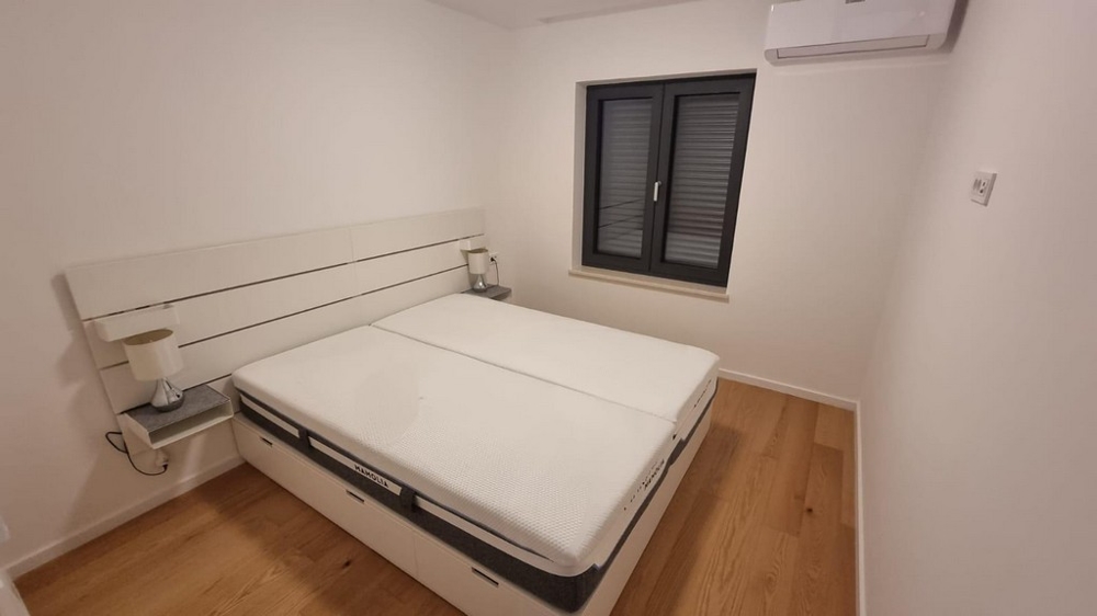 Bedroom of an apartment in Croatia with a double bed and minimalist design.
