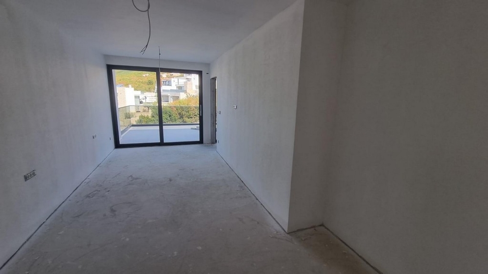 Unfurnished living space in an apartment in Croatia with large windows and terrace access.