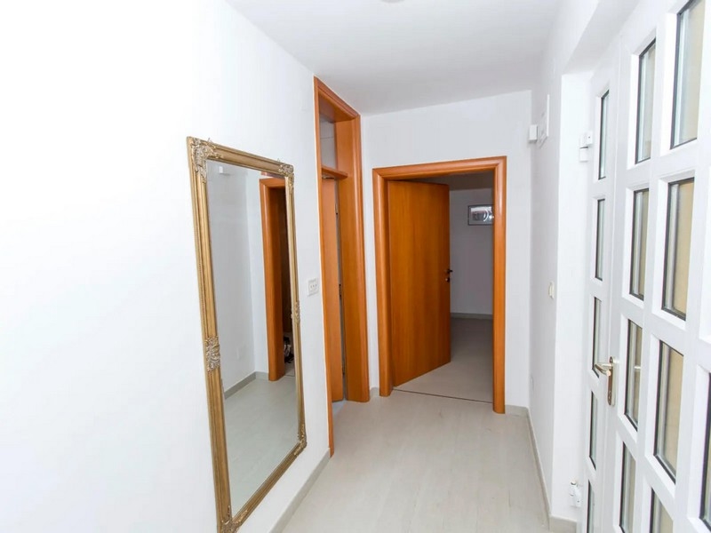Hallway with white walls, large mirror and doors leading to different rooms in the apartment.