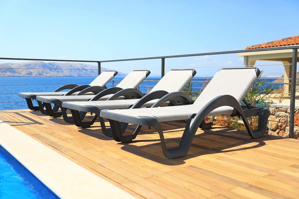 View of the lounging area by the swimming pool with a view of the sea in the Senj region.