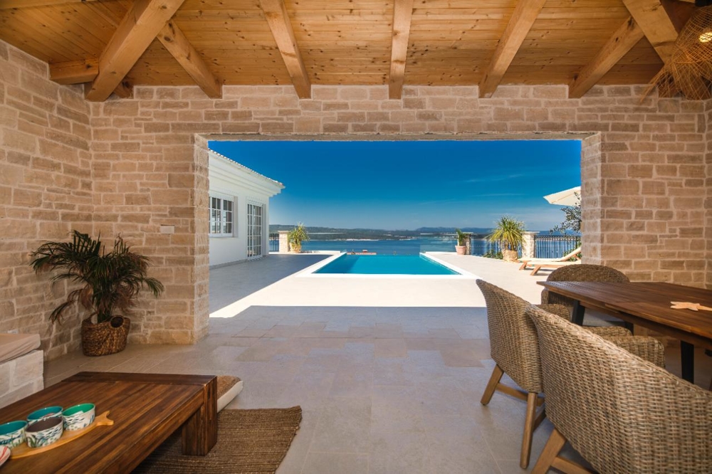 Covered dining area with barbecue grill and views of the pool and the sea.