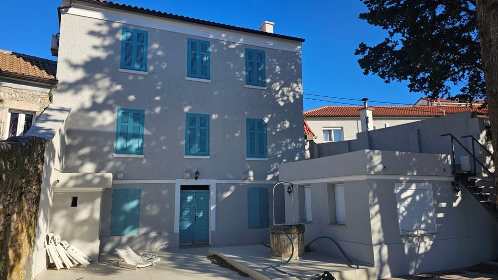 Buy a house Croatia - Panorama Scouting H2871: Front view of the Mediterranean townhouse with blue shutters and entrance stairs.