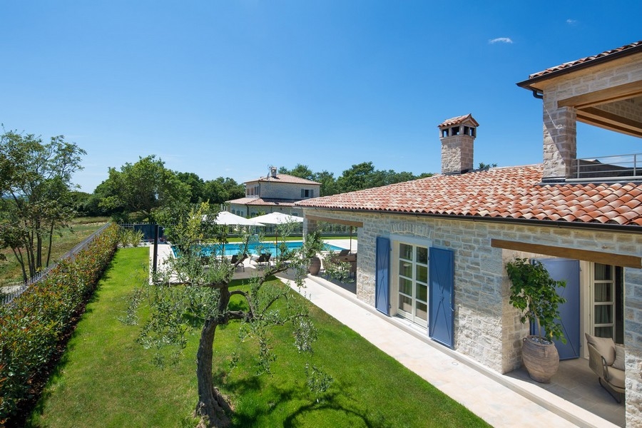 Aerial view of a high quality stone villa with pool in Croatia, surrounded by green areas and clear skies, available at Real Estate Croatia H2878