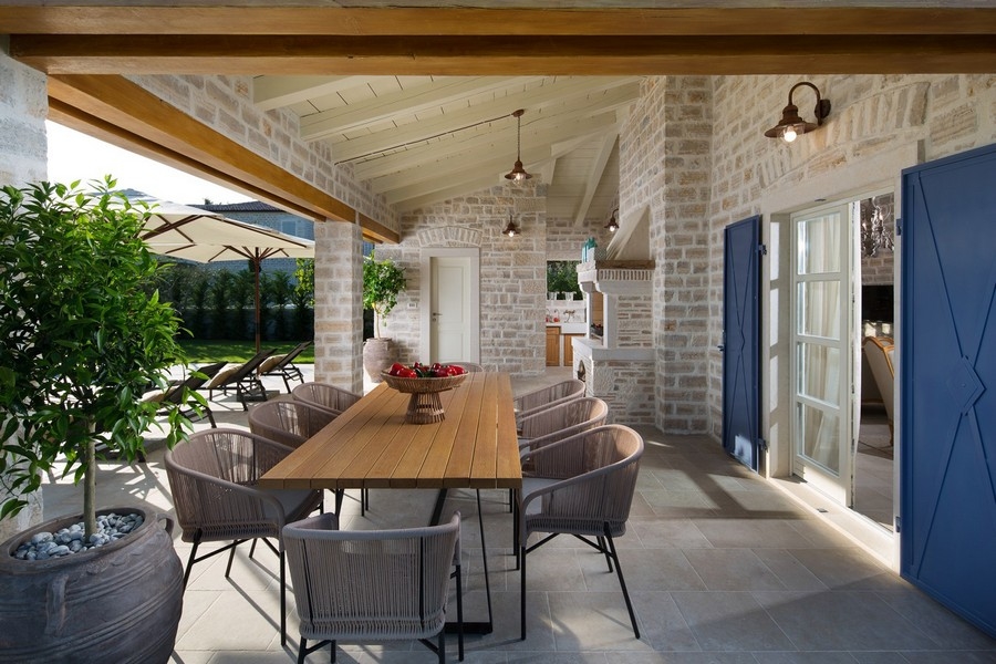 Covered outdoor dining area with large wooden table and modern chairs in a Croatian villa, included in real estate Croatia