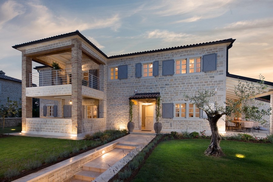 Luxurious two-story villa with illuminated facade at dusk, well-kept garden and stone path - Real Estate Croatia
