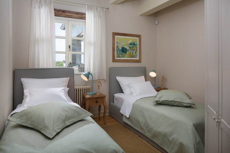 Cozy bedroom with two single beds, green bed linen and artwork on the wall - Real Estate Croatia