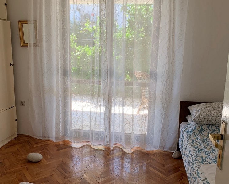 Bright bedroom with parquet floors and window views of the green outdoor areas of the house in Peljesac