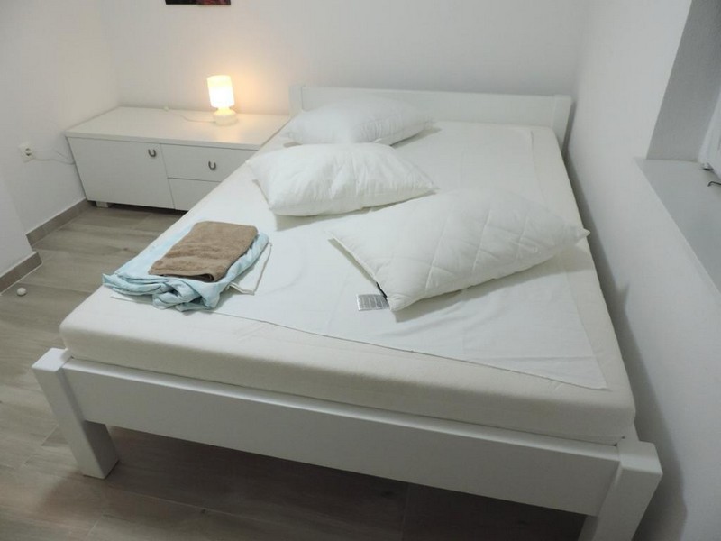 Simple bedroom with a large bed and white furniture, clean linens laid out