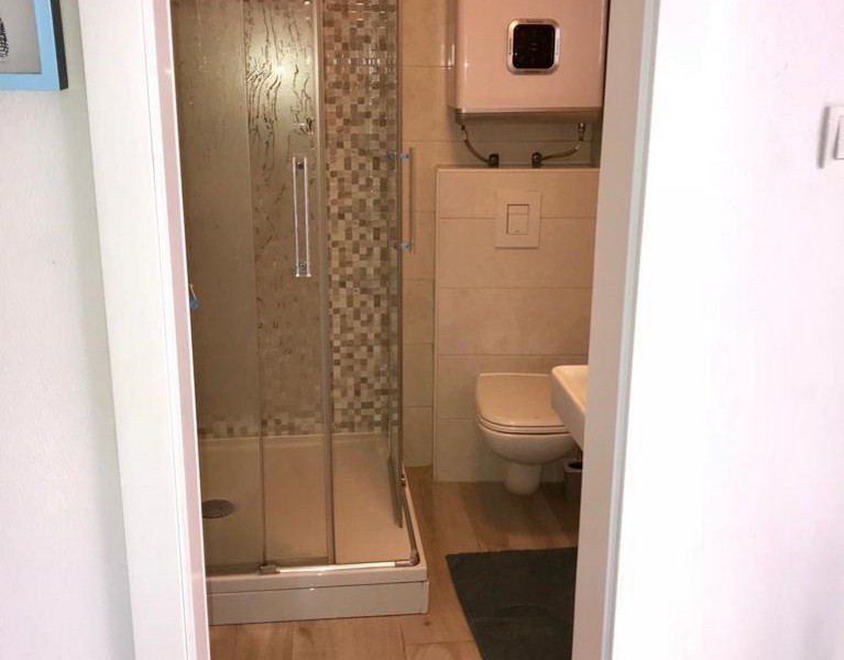 Bathroom in stone house with shower cubicle, toilet and water heater, modern accents in the tiles