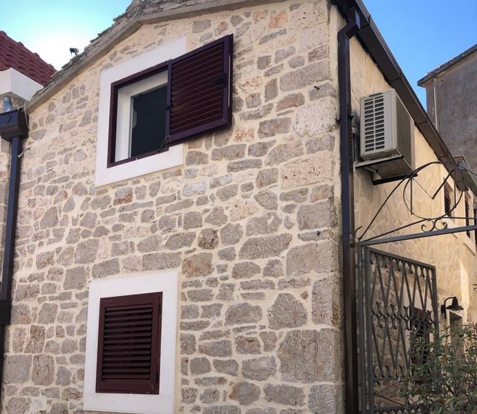 Facade of charming stone house with closed wooden shutters and air conditioning in the historic center of Primošten