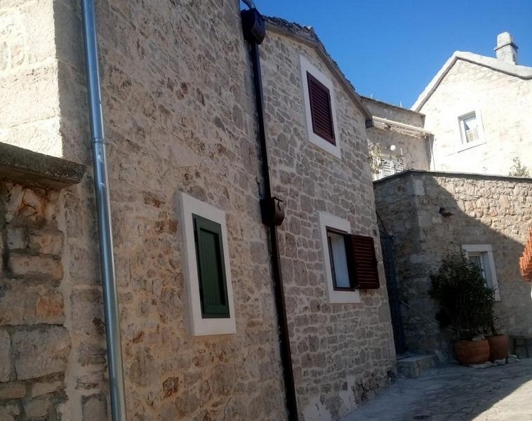Paved path leads to the entrance of the traditional stone house in Primošten, surrounded by other historical buildings