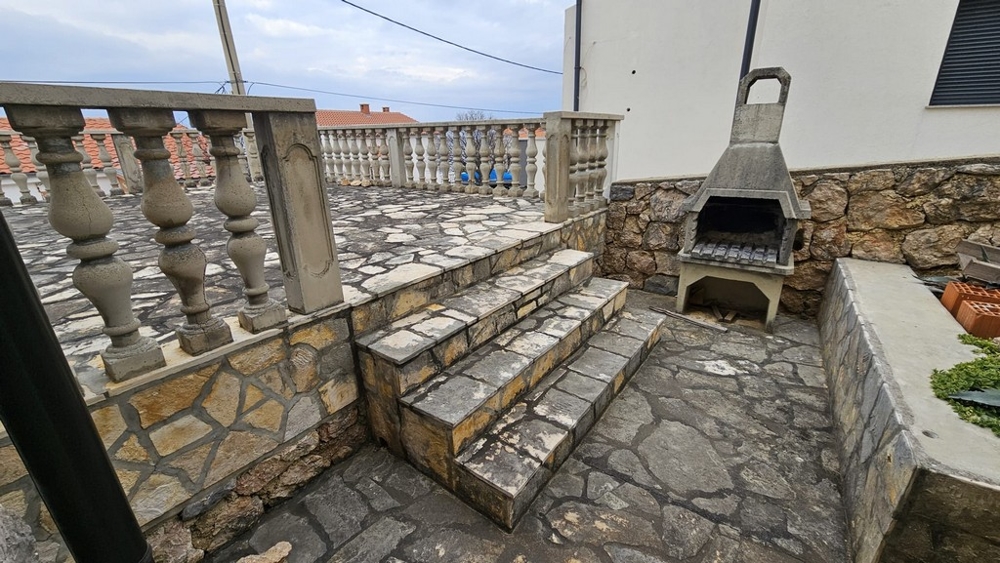 Outdoor area with barbecue area and stone stairs in the house for sale in Karlobag