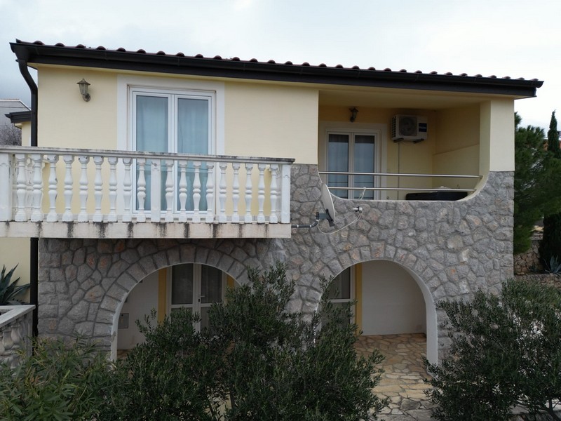 Front view of yellow house for sale in Karlobag with balcony and stone arches