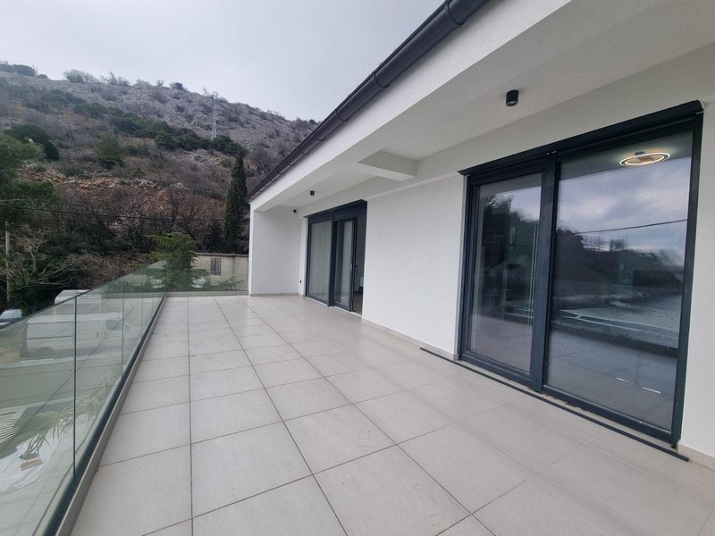 Large empty terrace of villa with glass railing and view of rocky landscape in Croatia
