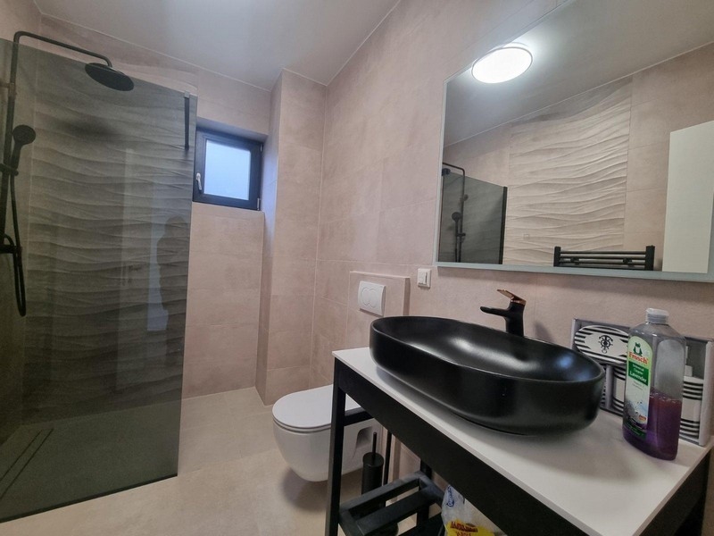 Modern bathroom with walk-in shower, black sink on white vanity and mirror in a Croatian villa