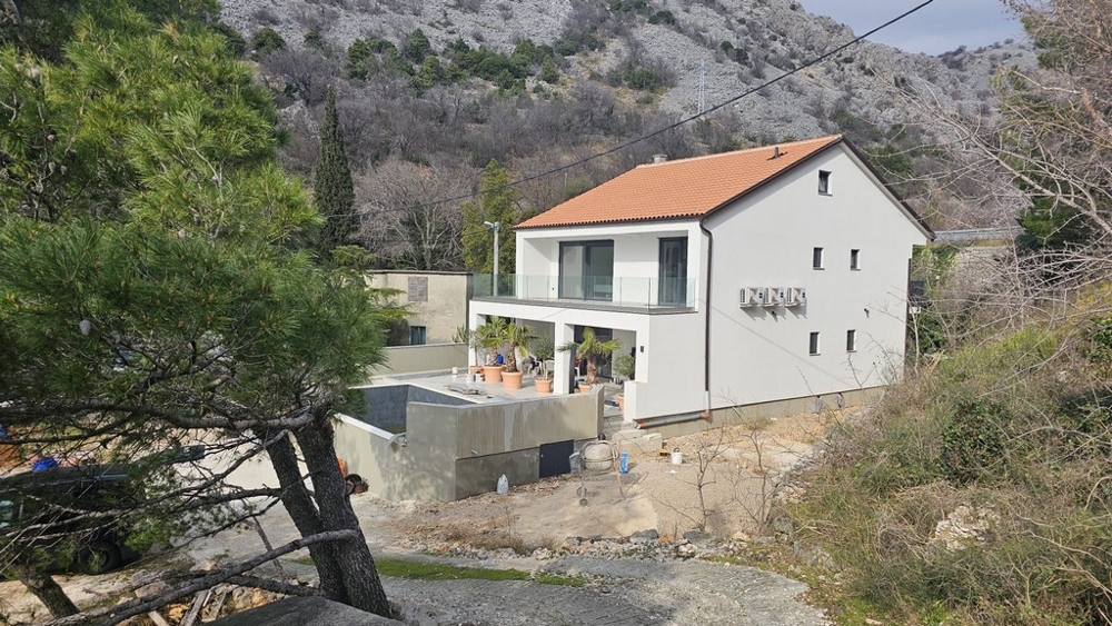 Rear view of modern villa with swimming pool surrounded by trees and rocks in Croatia