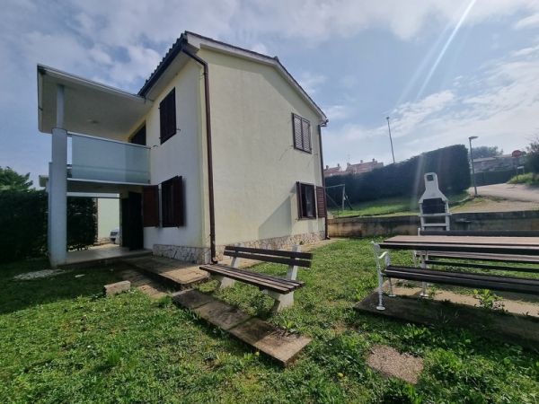 Rear view of a house for sale in Istria with a terrace and lawn.