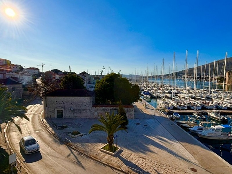Panoramic shot of a marina at sunrise in Croatia with boats and palm trees on the shore