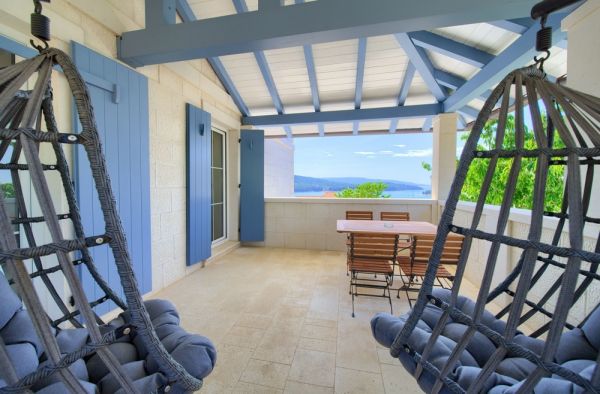 Sea view terrace in a property listing in Croatia, with two hanging egg swings and a dining table under an open, shaded gazebo
