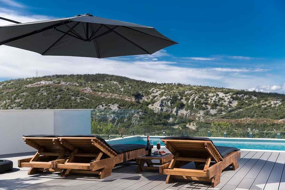 View of the lounging area of ​​the property with a view of the swimming pool and the mountains in the background.